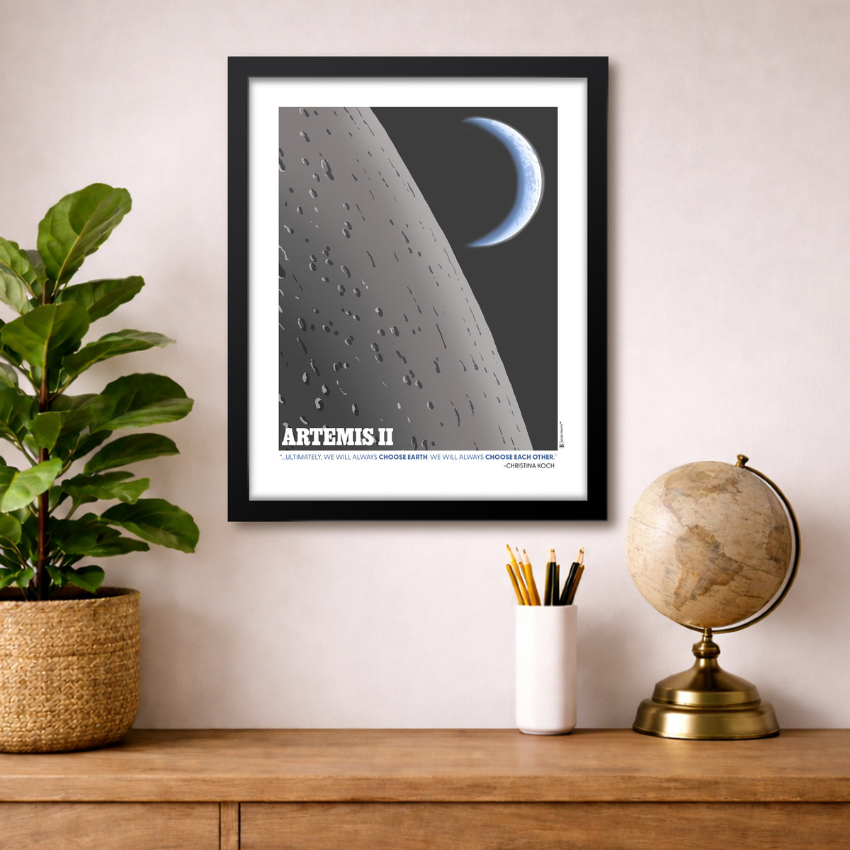 Framed space-themed poster on a wall above a wooden surface with decor items.